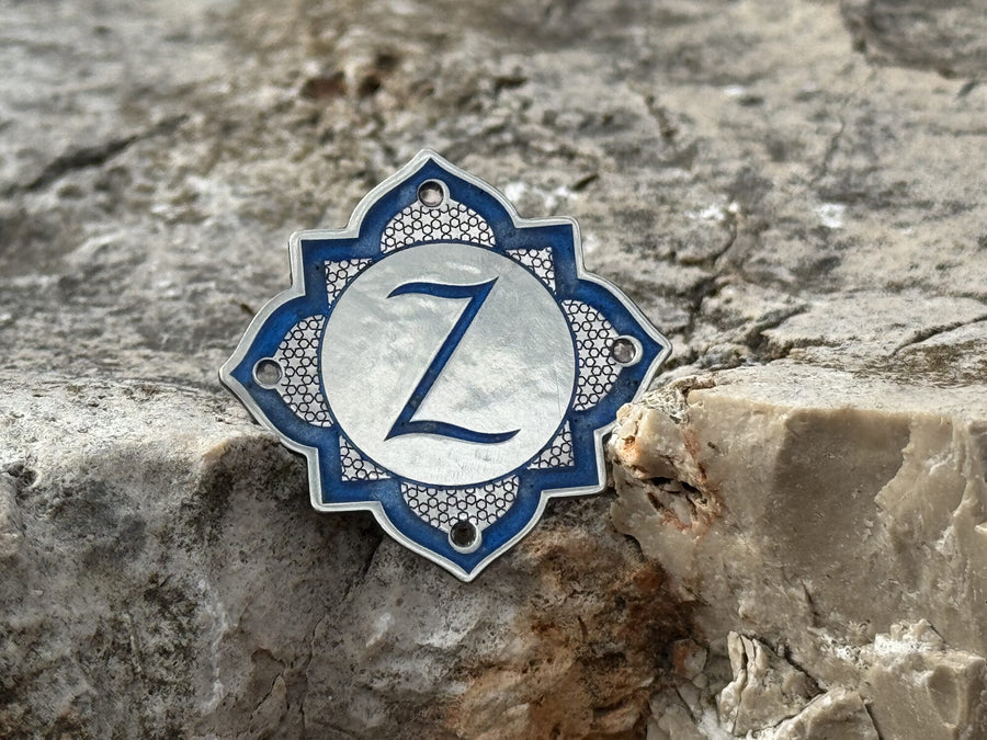 Monogram badge on a pierced quatrefoil
